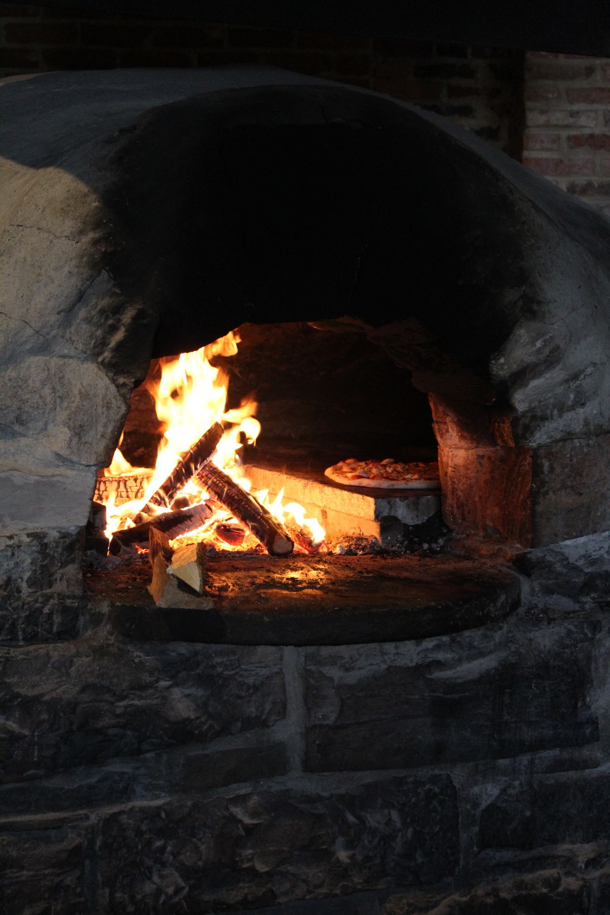 Pizza cooking in a blazing stone oven